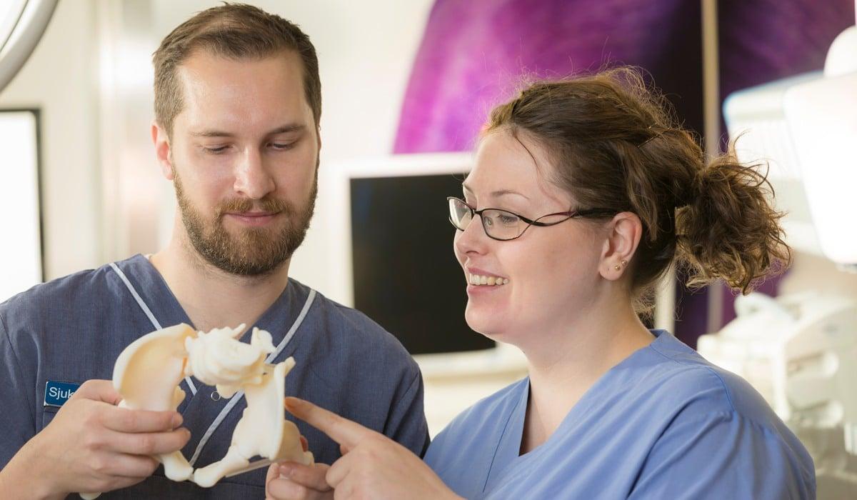 Två vårdmedarbetare som håller i en 3D-printad skelettdel.