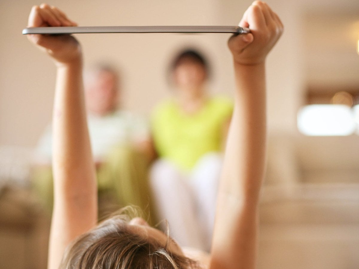 Ett barn ligger och läser på läsplatta