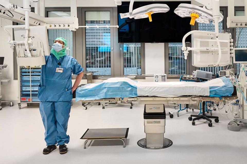 Operationssal där en vårdmedarbetare i skyddskläder står invid en operationsbädd