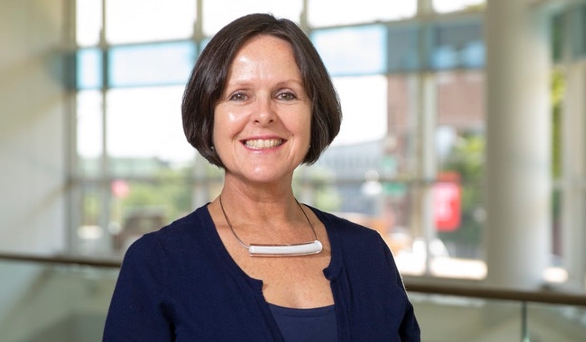 En kvinna står framför en glasvägg.