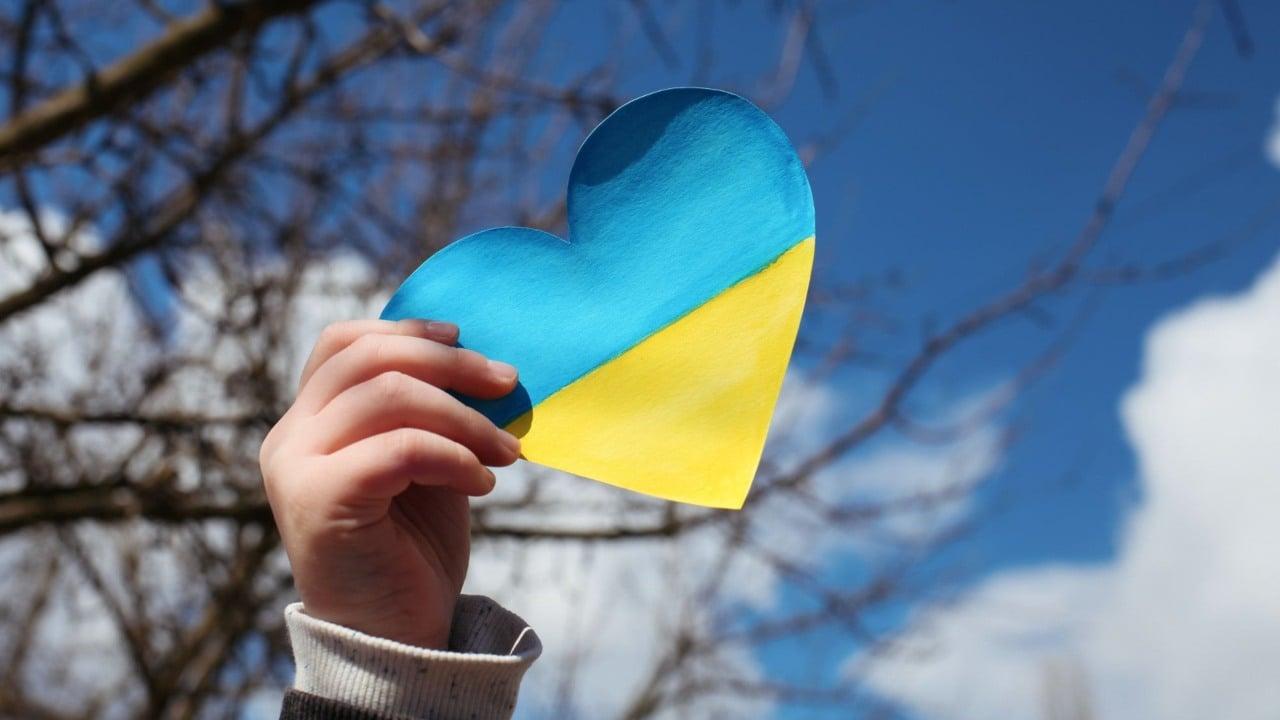 Person som håller i ett hjärtformad ukrainsk flagga