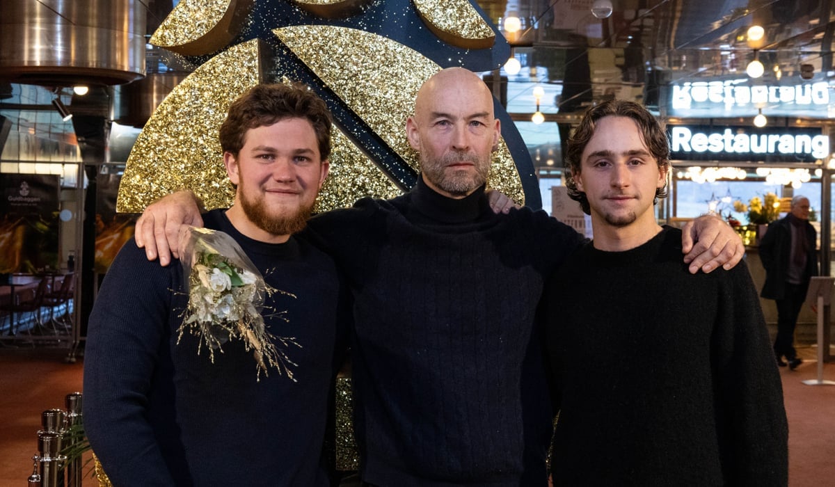 Tre leende män tittar in i kameran med en glittrig Guldbaggelogotyp i bakgrunden.