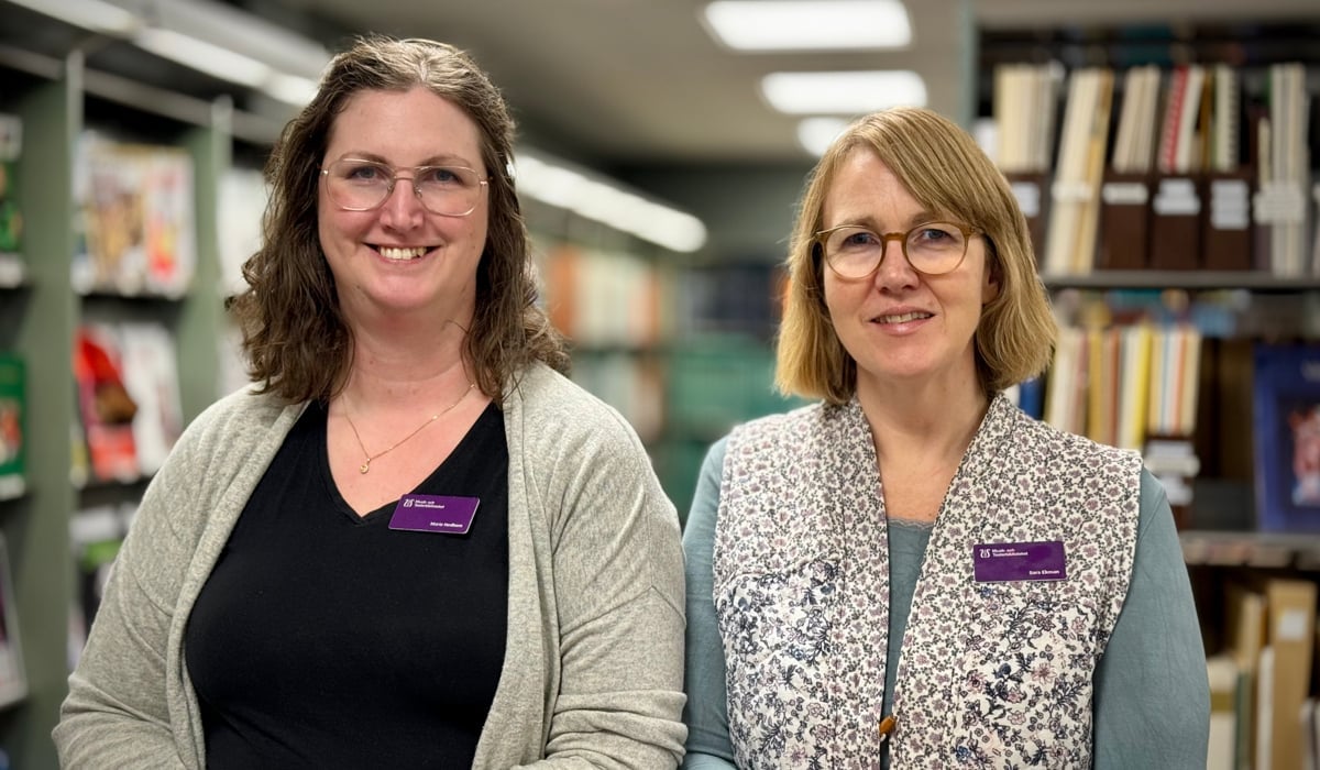 Två kvinnor som står bredvid varandra i ett bibliotek.