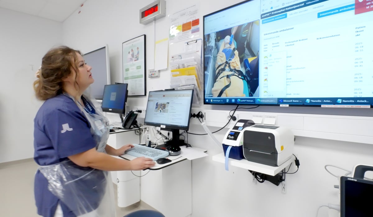 En kvinna i sjukhuskläder står och läser på en skärm