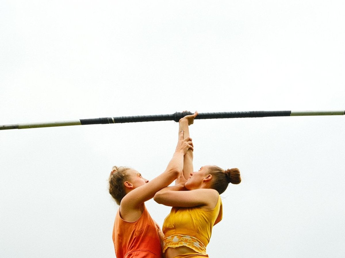 Två cirkusartister står med färgglada kläder mot varandra i halvfigur.