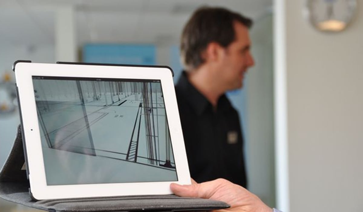 Foto på en ipad med en bild på fastighet. I bakgrunden syns en man suddigt.